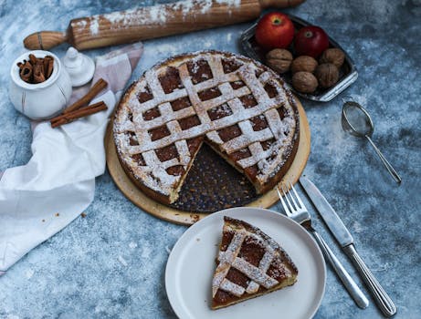 Tarte aux pommes maison avec une croûte en treillis, servie avec des noix et des pommes, sur une table en pierre.